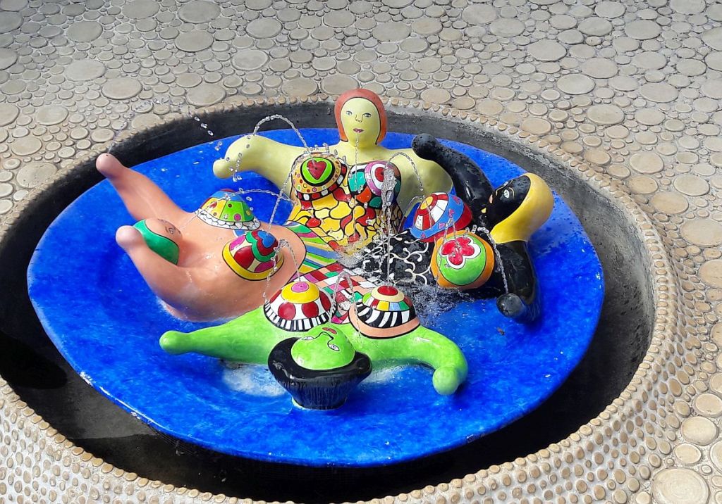 Vier verschieden farbige Frauenfiguren in einem Pool