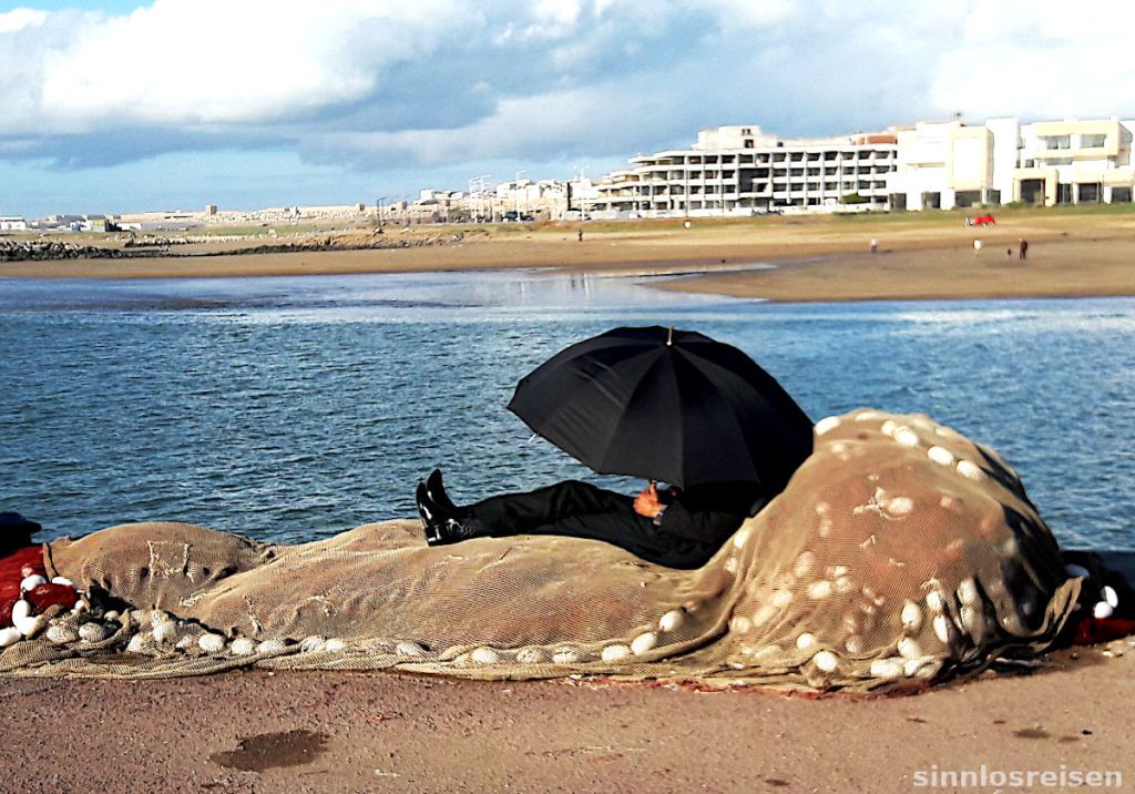 Mann schläft auf Fischernetz mit Regenschirm