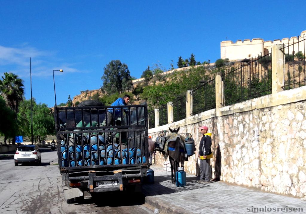 Männer laden Gasflaschen vom Lkw auf einen Esel