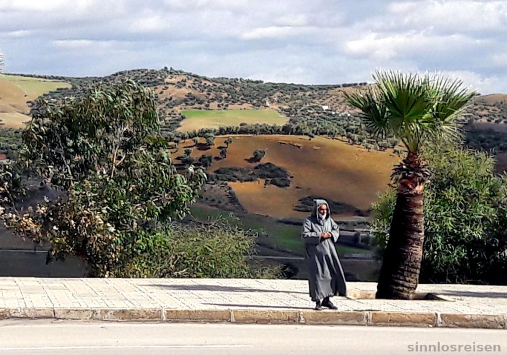 Mann in Berberkapuze steht am Straßenrand