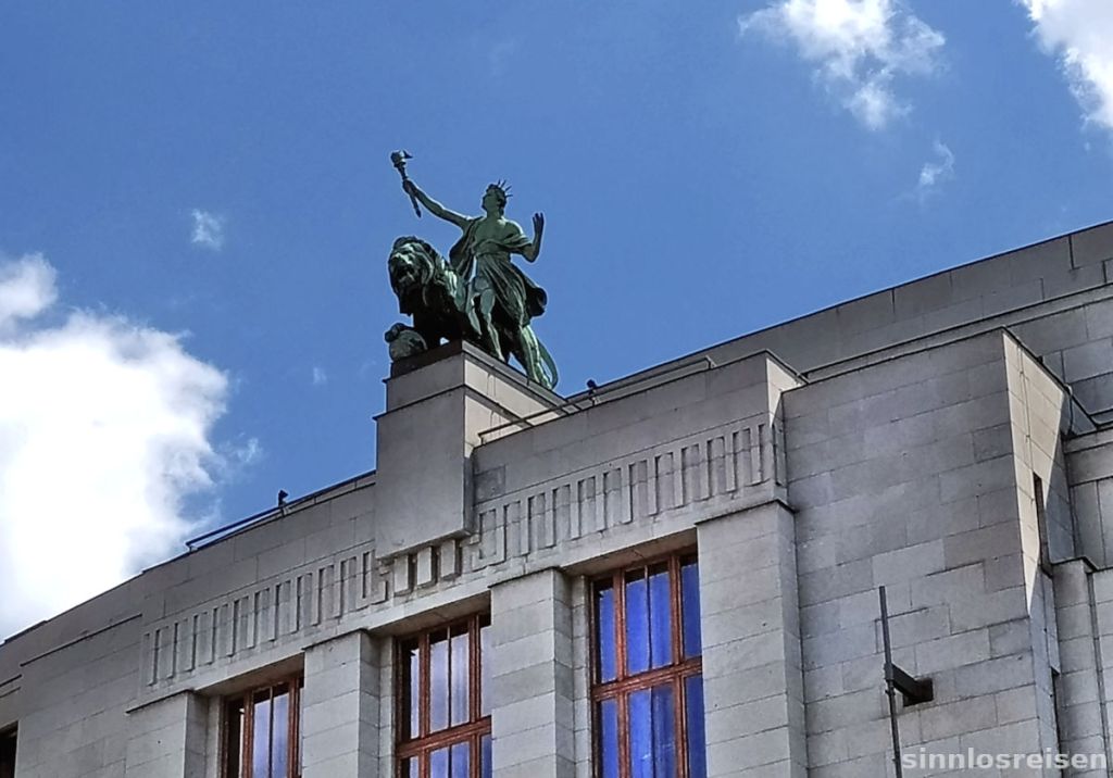 Statue mit Fackel reitet auf Löwen auf Hausdach