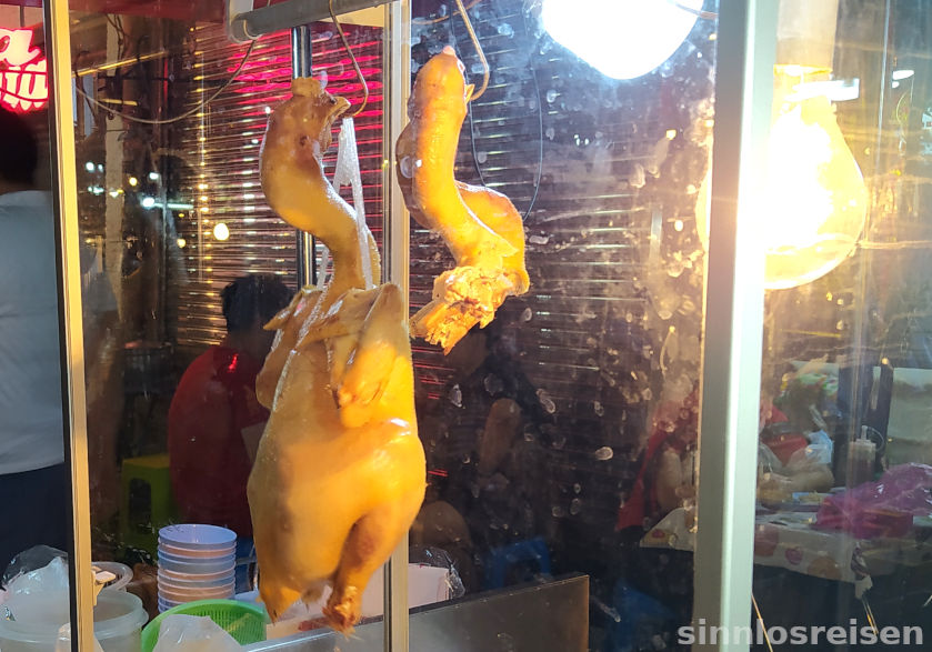 Eine und eine halbe gebratene Gans hängen am Stand