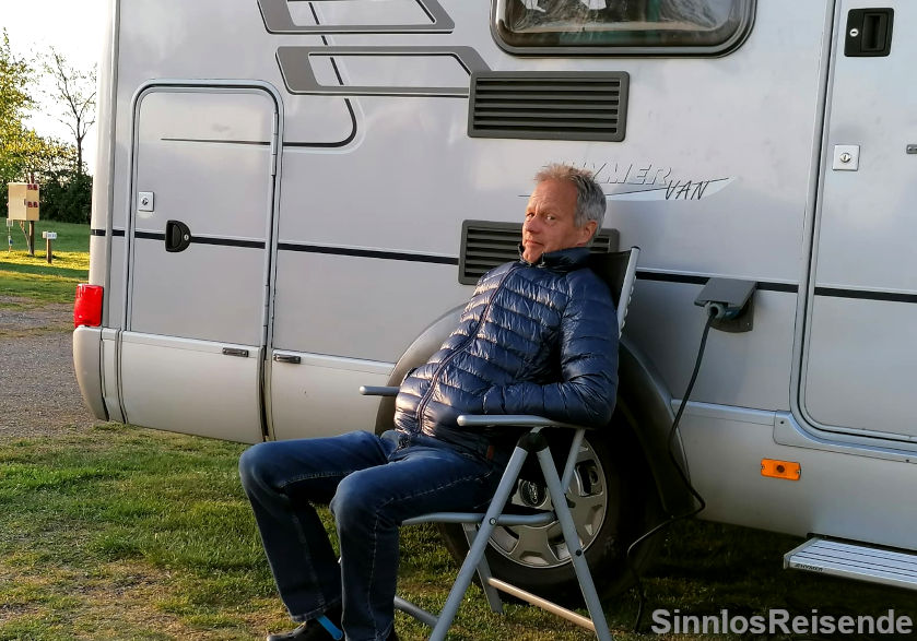 Mann sitzt frierend vor dem Wohnmobil